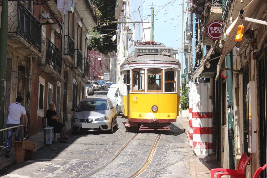 Eine gelbe Straßenbahn in einer schmalen Gasse in Lissabon
